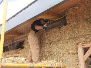 man installing straw bale on top course