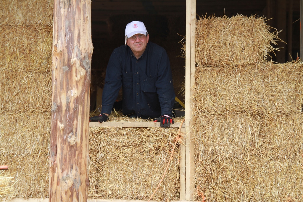 man standing by straw bale wall