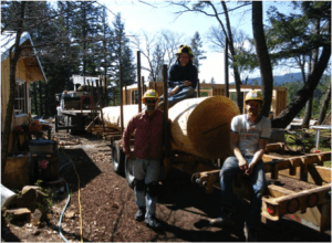 three men with large log on a trailer
