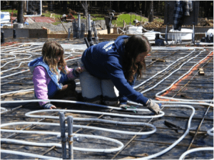 woman and child installing radiant floor heat tubing