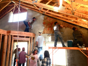 People applying plaster to straw bale walls