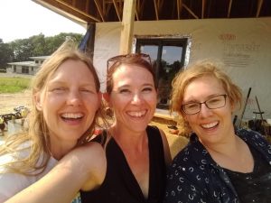 Happy women in front of straw bale house