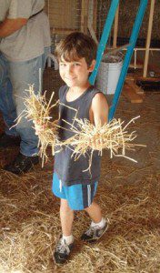 child holding handfuls of straw