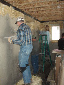 People plastering a straw bale house