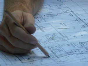 hand with pencil on construction drawings