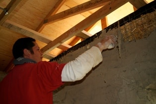 man plastering straw bale wall