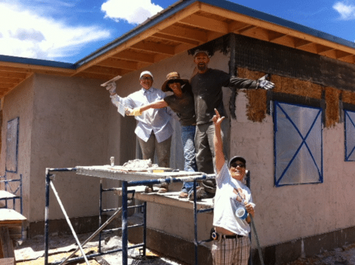 people plastering straw bale house