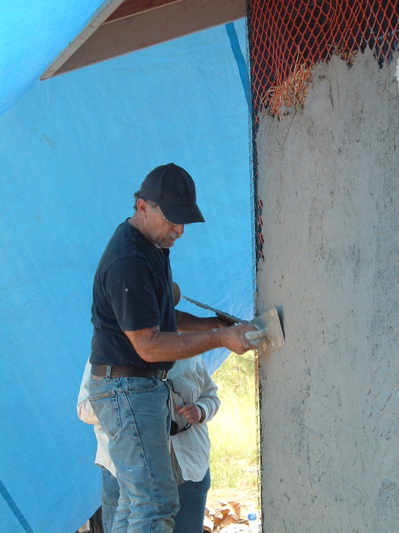 man plastering straw bale house