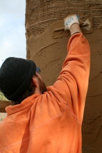 man plastering straw bale wall