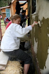 woman applying final plaster on straw bale wall
