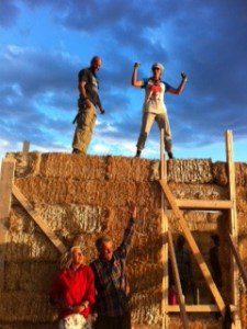 people standing atop straw bale wall