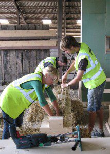 workers adjusting a straw bale for the wall assembly