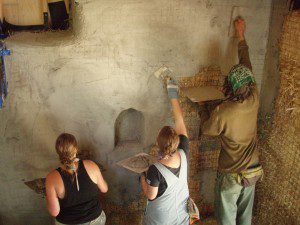 people plastering straw bale wall